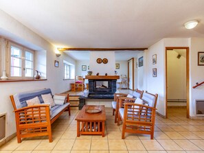A cozy living room with a fireplace, wooden furniture, and a tiled floor.