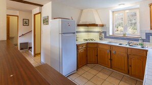 A kitchen with wooden cabinets, a white refrigerator, a tiled backsplash, and a window with a view.