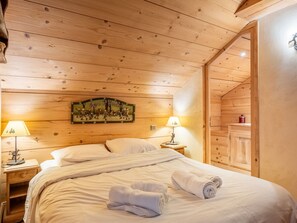 A cozy wooden room with a bed, two bedside lamps, and a decorative wall piece. - Chalet central village mountain view - 11 guests (La Clusaz)