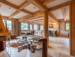 A spacious living area with a high ceiling, wooden beams, a dining table, and a sofa with a fur throw. - Chalet central village mountain view - 11 guests (La Clusaz)