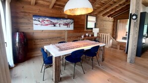 A wooden interior with a dining table, chairs, a pendant light, and a painting on the wall. - Prestige chalet, mountain view - 10 guests (La Plagne Montalbert)
