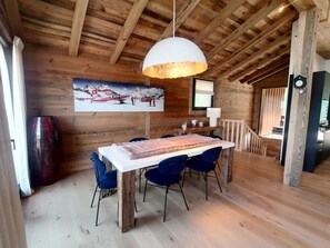 A wooden interior with a dining table, chairs, a pendant light, and a painting on the wall. - Prestige chalet, mountain view - 10 guests (La Plagne Montalbert)