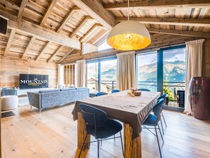 Ein geräumiges Zimmer mit Holzbalkendecke, einem großen Esstisch und einer Couch.