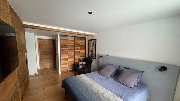 A bedroom with a bed, a TV, a wardrobe, and a door leading to another room. - Prestige chalet, mountain view - 10 guests (La Plagne Montalbert)
