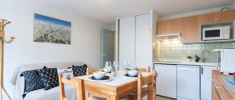 A compact kitchen with a dining table, chairs, a microwave, and a dishwasher.