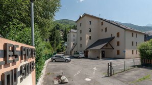 Ein Parkplatz mit einem Gebäude im Hintergrund, einem Schild mit großen Buchstaben und einem Berg in der Ferne.