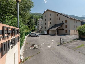 Ein Parkplatz mit einem Gebäude im Hintergrund, einem Schild mit großen Buchstaben und einem Berg in der Ferne.
