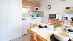 Eine kleine Küche mit Holzausstattung, einer Mikrowelle, einem Toaster und einer Uhr an der Wand.