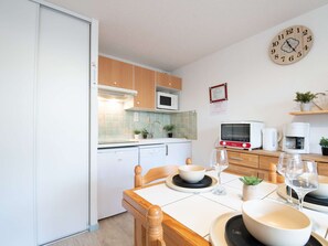 Eine kleine Küche mit Holzausstattung, einer Mikrowelle, einem Toaster und einer Uhr an der Wand.