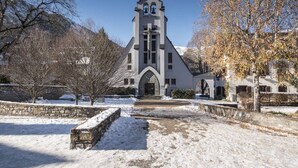 Eine Kirche mit einem Glockenturm, Steinmauern und einem verschneiten Innenhof.