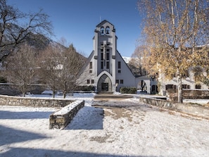 Eine Kirche mit einem Glockenturm, Steinmauern und einem verschneiten Innenhof.