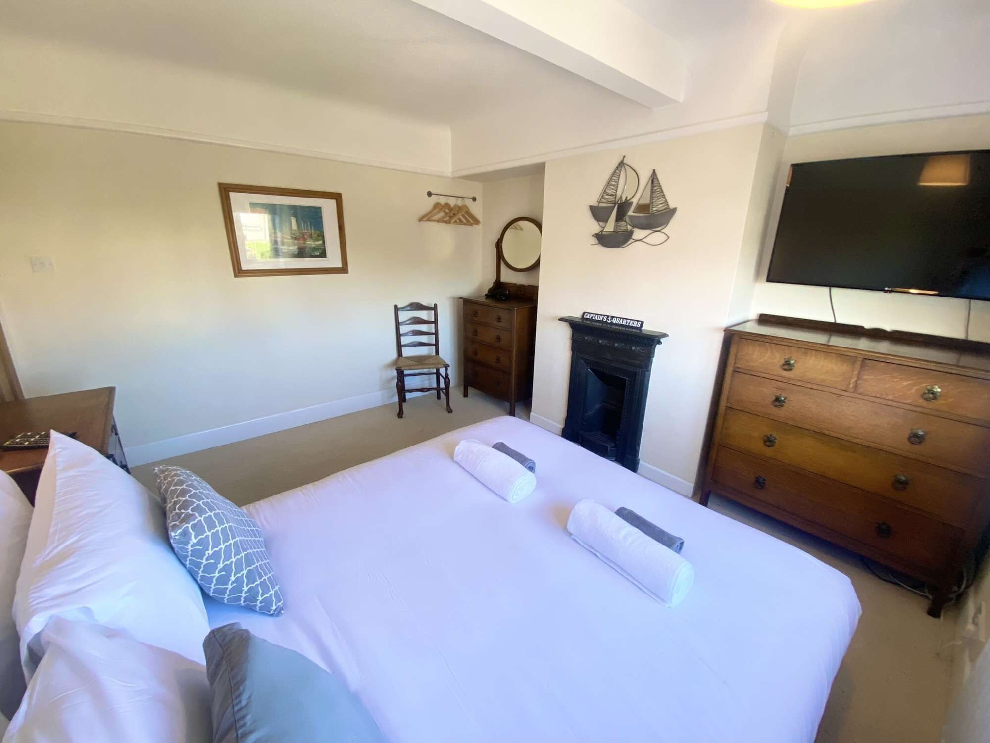 A hotel room with a bed, a dresser, a chair, a television, and a fireplace.