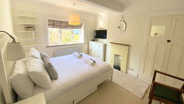 A bedroom with a bed, bedside lamp, TV, dresser, and a small mirror. - Near the River and Marinas, quick walk to town Large Garden and off street parking for 3 cars (Lymington)