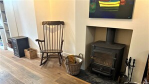 A room with a wooden floor, a rocking chair, a fireplace with a TV mounted above it, and a basket of items on the floor. - Near the River and Marinas, quick walk to town Large Garden and off street parking for 3 cars (Lymington)