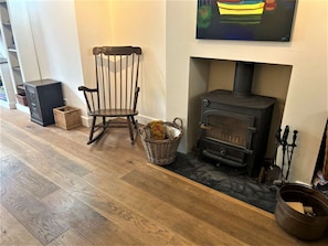 A room with a wooden floor, a rocking chair, a fireplace with a TV mounted above it, and a basket of items on the floor. - Near the River and Marinas, quick walk to town Large Garden and off street parking for 3 cars (Lymington)