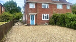 A two-story brick house with a blue door, a gravel driveway, and a wooden fence. - Near the River and Marinas, quick walk to town Large Garden and off street parking for 3 cars (Lymington)