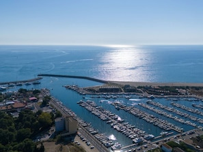 An aerial view of a marina with numerous boats docked, a pier extending into the water, and a clear sky. - Air-conditioned house near the beach - 6 guests (Saint-Cyprien)