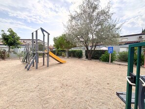 A playground with a slide and climbing structures, surrounded by sand and trees. - Air-conditioned house near the beach - 6 guests (Saint-Cyprien)