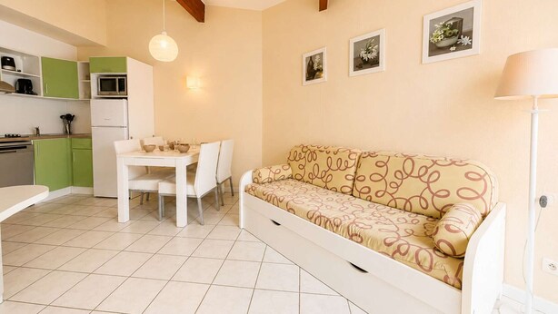 Un espai habitable compacte amb una cuineta, una taula de dinar i un sofà.