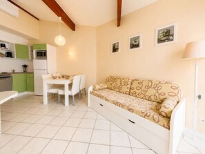 A compact living space with a kitchenette, a dining table, and a sofa. - Air-conditioned house near the beach - 6 guests (Saint-Cyprien)
