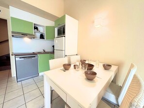 A compact kitchen with a dining area, including a table with bowls and glasses, and a microwave above the counter. - Air-conditioned house near the beach - 6 guests (Saint-Cyprien)