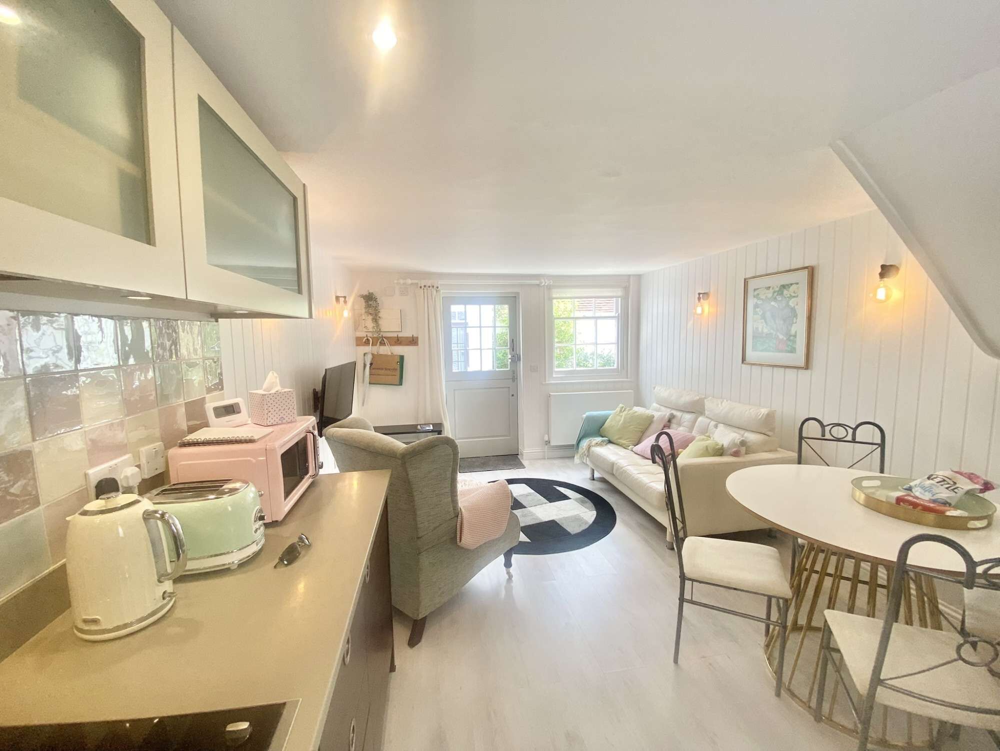 Un espace de vie compact comprenant un coin cuisine, un coin repas et un espace détente avec un canapé et des fauteuils.