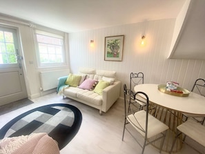 A living room with a white sofa, a round dining table, and a black and white rug. - Newgate Cottage by NewFo dot Rest (Lymington)