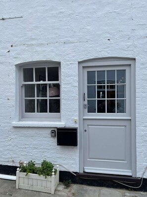 A white building with a single door and a small window. - Newgate Cottage by NewFo dot Rest (Lymington)