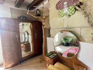 Habitació amb un armari de fusta, un gran mirall i una làmpada de disseny amb forma d'arbre.