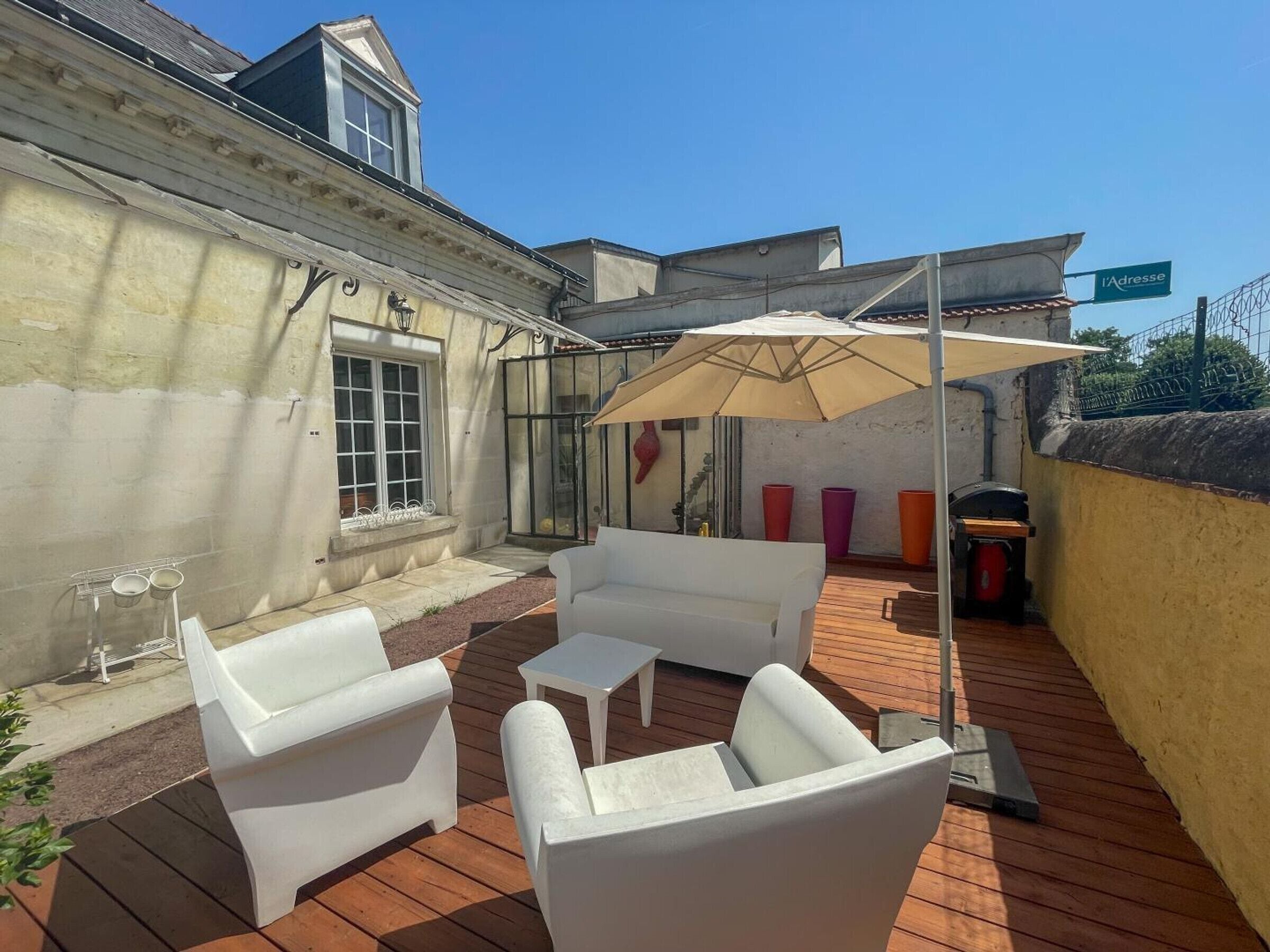 Eine Terrasse mit weißen Möbeln, einem Tisch und einem Sonnenschirm.