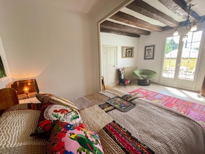 A cozy room with a bed, a chair, a lamp, and a view of the outdoors through a door. - Gîte in Touraine, pets welcome - 4 guests (Rochecorbon)