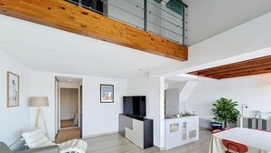 Un espacio moderno de estar con zona superior, mesa de comedor y cocina.
