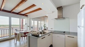 Una cocina moderna con una isla central, un comedor con vistas y un balcón con barandilla.
