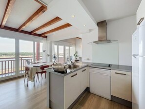 Eine moderne Küche mit Kochinsel, ein Essbereich mit Blick und ein Balkon mit Geländer.