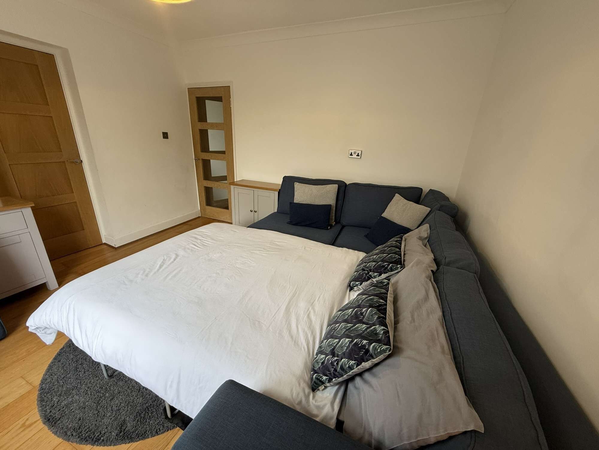 A bedroom with a bed, a desk, and a wardrobe.