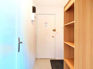 A hallway with a white door, a wooden shelf unit, and a tiled floor. - Cozy apartment - 7 guests (Le Corbier)
