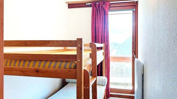 Ein Stockbett mit Holzrahmen und einem Fenster mit Vorhängen.