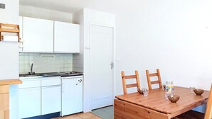 Eine kleine Küche mit weißen Schränken, einem Herd und einem Esstisch mit Stühlen.