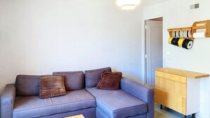 Ein modernes Wohnzimmer mit einem grauen Sofa, einem Holzschrank und einer Pendelleuchte.