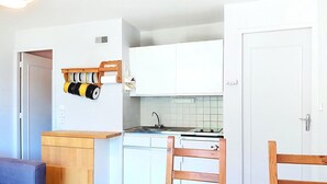 Eine kleine Küche mit weißen Schränken, einem Holztisch und einem Stuhl.