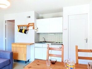 Eine kleine Küche mit weißen Schränken, einem Holztisch und einem Stuhl.