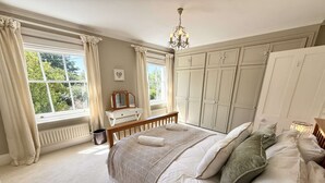 A bedroom with a large bed, a chest of drawers, a radiator, and a window with curtains. - Springfield by NewFo dot  rest (Milford on Sea)
