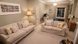 A living room with two beige sofas, a lamp, a framed photo collage, and a window with curtains. - Springfield by NewFo dot  rest (Milford on Sea)