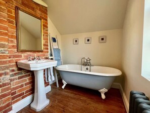 Ein Badezimmer mit einer freistehenden Badewanne, einem Standwaschbecken und einem großen Spiegel.