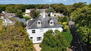 A residential area with a prominent white house featuring a gabled roof and multiple windows. - Springfield by NewFo dot  rest (Milford on Sea)