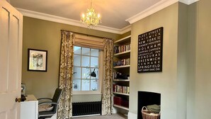 A room with a radiator, a bookshelf, a desk with a chair, a window with curtains, and a chandelier. - Springfield by NewFo dot  rest (Milford on Sea)