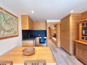 Eine kompakte Küche mit Holzausstattung, einem Esstisch mit Stühlen und einer Karte an der Wand.
