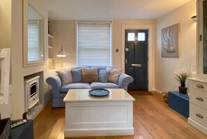 A living room with a sofa, a coffee table, a fireplace, and a door. - Starboard Light by NewFo dot Rest (Lymington)