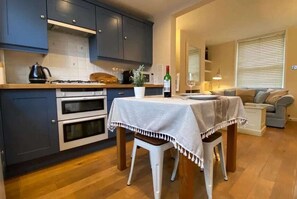 Cozinha compacta com área de refeições, um sofá e uma janela com persianas.