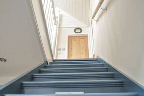 A staircase leading to a wooden door with a circular light fixture above it. - Starboard Light by NewFo dot Rest (Lymington)